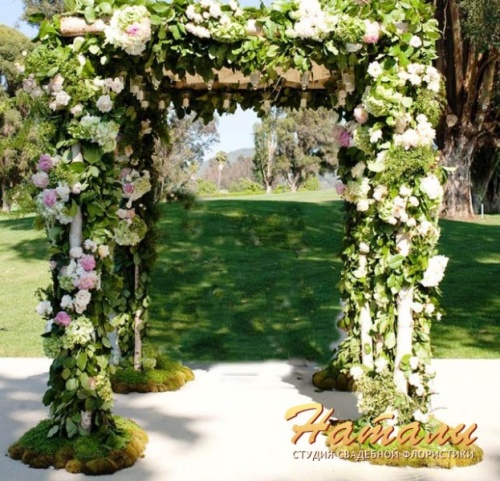 свадебная арка украшена мхом и цветами